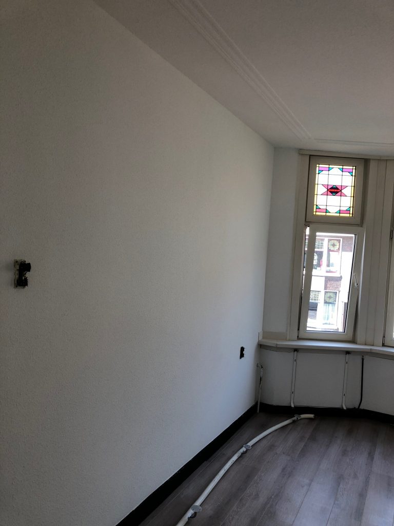 Spackgespoten wand en plafond bij glas-in-loodramen in Schiedam