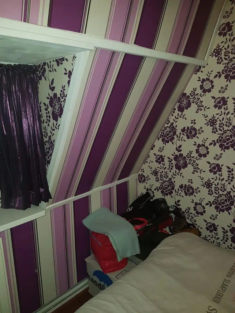 Slaapkamer met oud gestreept en gebloemd behang vóór renovatie